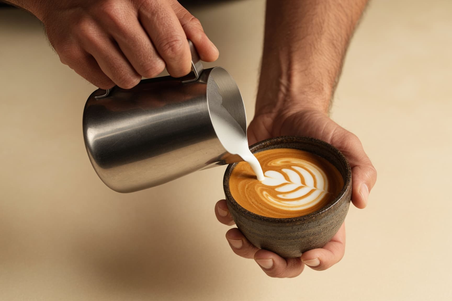 A barista pouring steamed milk