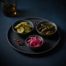 Three bowls of pickles — cucumber, gherkin, pink onion