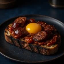 Sausage and cooked-down tomato on grilled bread, a raw yolk on top